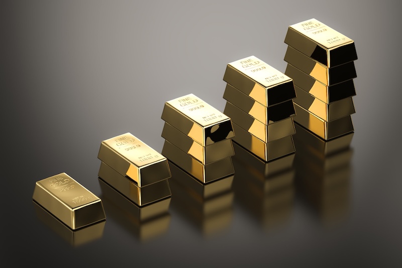 Gold bullion bars and coins with upward trending price